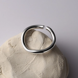 Macro shot of polished silver wavy irregular ring on textured stone surface background