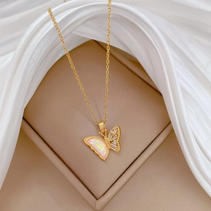 Detailed macro view of gold-plated butterfly pendant with pink resin and shiny zircon stones