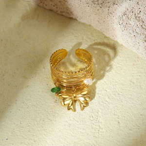Detailed view of gold multi-layer ring with bow, pearl, and green stone charms