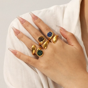 Detail of vintage gold-plated rings with natural green stones on female hand