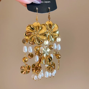 Nahaufnahme vintage goldener Blumenohrringe mit Blütenblättern und weißen Perlenquasten