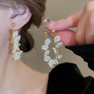 Élégantes boucles d'oreilles fleurs blanches en acrylique avec métal doré sur un mannequin