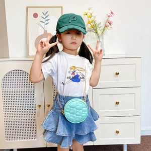 Kids quilted mint green heart chain bag styled with casual outfit and baseball cap