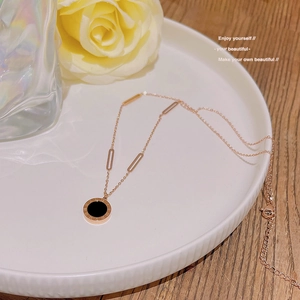 Macro shot of 18K rose gold necklace pendant with Roman numerals and black inlay