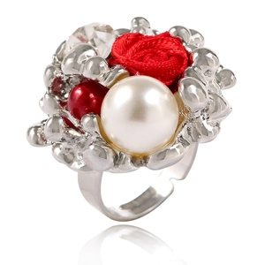 Gros plan de la rose en velours rouge et perle sur bague en métal argenté fondu