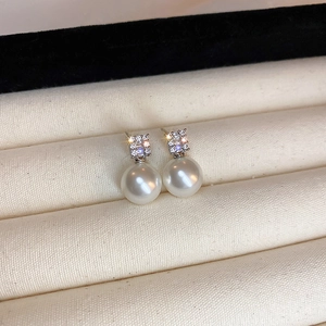 Vue macro de boucles d'oreilles en perles avec zircons sur un plateau à bijoux beige