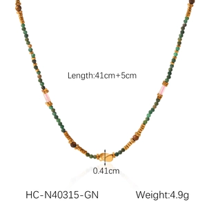 Detail view of colorful beaded necklace with green natural stones and golden metal charm
