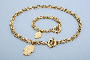 Detail of gold Hamsa hand pendant and OT toggle clasp on stainless steel necklace set
