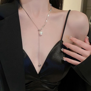 Detailed view of a silver pearl tassel necklace with adjustable drawstring on model