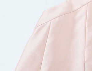 Détail de la texture du tissu en satin rose et de la couture d'épaule de cette robe élégante