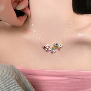 Gros plan d'un collier doré avec des pendentifs fleurs en cristal sur mannequin