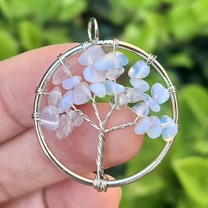 Detail of tree of life pendant with colorful wire wrap and opal stones held in hand