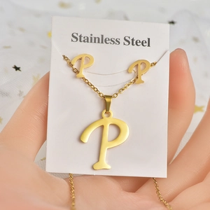Dettaglio del set di collana e orecchini con lettera P in acciaio inox dorato