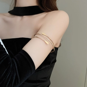 Detailed view of a minimalist layered golden arm cuff with twisted texture on a model