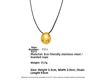 Detail showing polished gold egg-shaped stainless steel pendant on black cord necklace