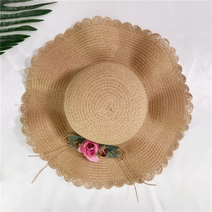 Chapeau de soleil en paille beige pour femme avec bord ondulé et fleurs, vue de dessus