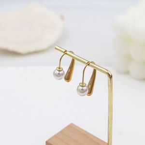 Detailed macro view of French style gold teardrop earrings with elegant white pearls