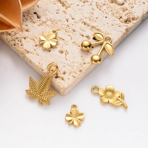 Golden stainless steel plant charms including clover and cherry on a beige stone base
