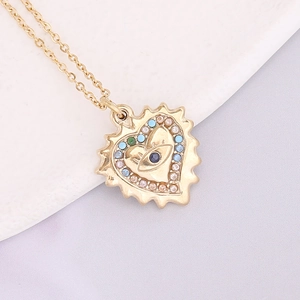 Macro shot of gold heart pendant with evil eye design and colorful small crystals