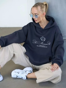 Detail of navy blue oversized hoodie featuring white The Movement Club letter print design
