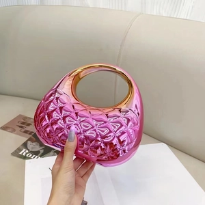 Close-up of fuchsia metallic clutch with quilted texture and gold round handle