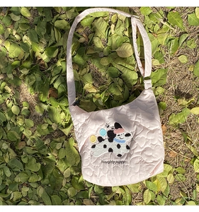 Detail of pink quilted tote bag with puppy embroidery and colorful buttons on nature background