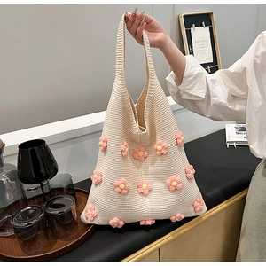Close-up of cream knitted tote bag featuring pink 3D crochet flowers and fine textures