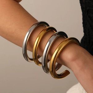 Minimalist C-shaped open bangles in gold and silver finish on a model's wrist