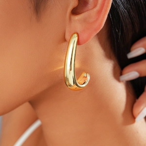 Close-up of polished gold drop earrings on model showcasing a sleek minimalist metal design