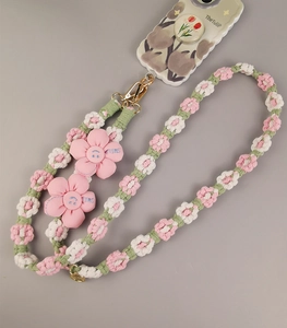 Macro shot of hand-woven phone lanyard featuring pink flower charms and smile embroidery