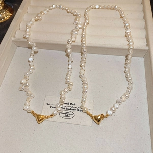 Detailed macro view of baroque pearl necklace with polished 18K gold heart pendant