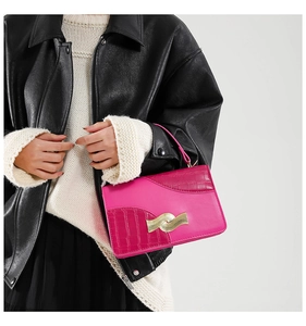 Detail of fuchsia leather handbag with crocodile pattern and wavy gold metal buckle