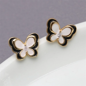 Macro detail of black and white enamel butterfly earrings with gold metal and clear gemstone
