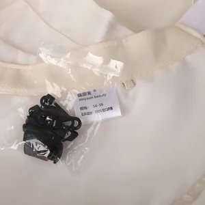 Detail view of white mesh sun hat featuring adjustable wind rope and washing label