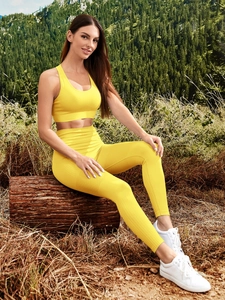 Detail of ribbed texture on yellow yoga vest and high-waisted leggings set outdoors