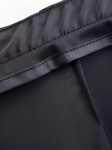 Close-up of black satin trousers showing smooth silk texture and high-density stitching