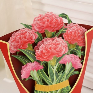 Detail of 3D pop-up greeting card featuring pink paper carnations and a gold ribbon bow
