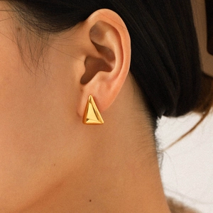 Close-up of minimalist 18K gold triangular stainless steel stud earring on ear