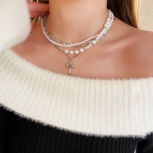 Detail of layered silver cross necklace with pearls shown on model neck for fashion styling