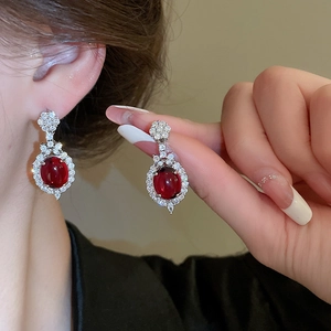 Detail of an Ancora red oval earring with white crystals on a silver metal base