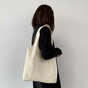 Detail view of cream white minimalist canvas shoulder bag with a functional front pocket
