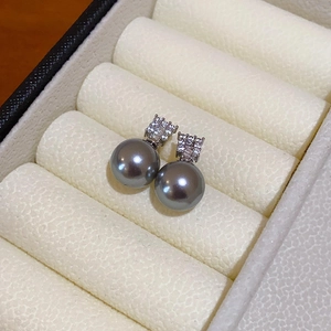 Macro detail of silver grey pearl earrings with cubic zirconia inlay on a jewelry tray