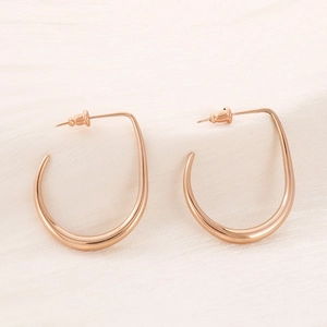 Macro view of rose gold U-shaped earrings featuring polished irregular curved metal lines