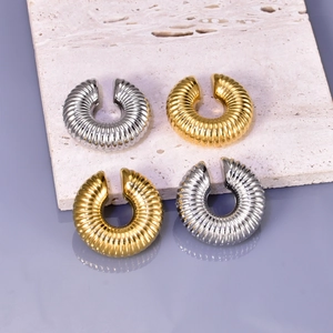 Macro detail of gold and silver textured hollow hoop earrings with spiral thread pattern