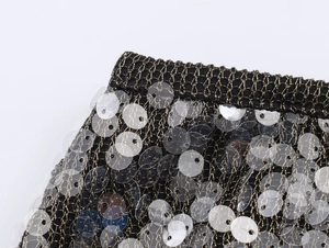 Details von schwarzem Strickrock mit goldenen Metallfäden und glänzenden Pailletten