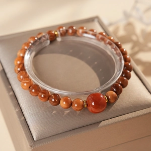 Macro detail of red agate beaded bracelet with gold spacer beads and central focal stone