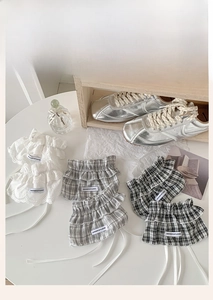 Close-up of lace leg warmers with ribbon bow and plaid ruffles on white table