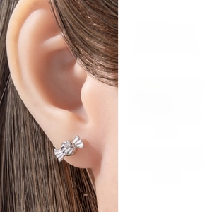 Macro shot of silver candy-shaped ear stud with center diamond and ear placement view