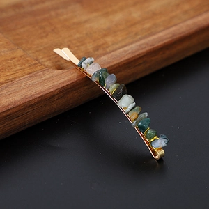 Detail view of gold bobby pin featuring natural colorful crystal stones and polished metal