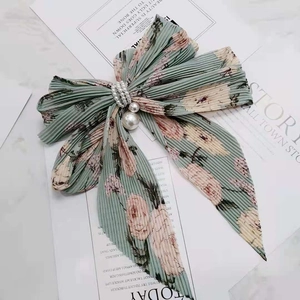 Barrette à nœud en mousseline à imprimé floral vert et pendentif perle sur magazine